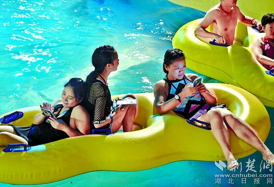 圖為:3名美女坐在橡皮游泳圈里各自玩著手機