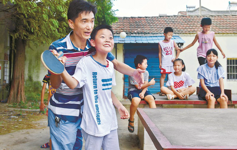 圖為:洪湖市濱湖辦事處洪獅小學內,老師周永杰義務幫學生補習數學之余,教孩子們打乒乓球 楚天都市報記者劉中燦攝