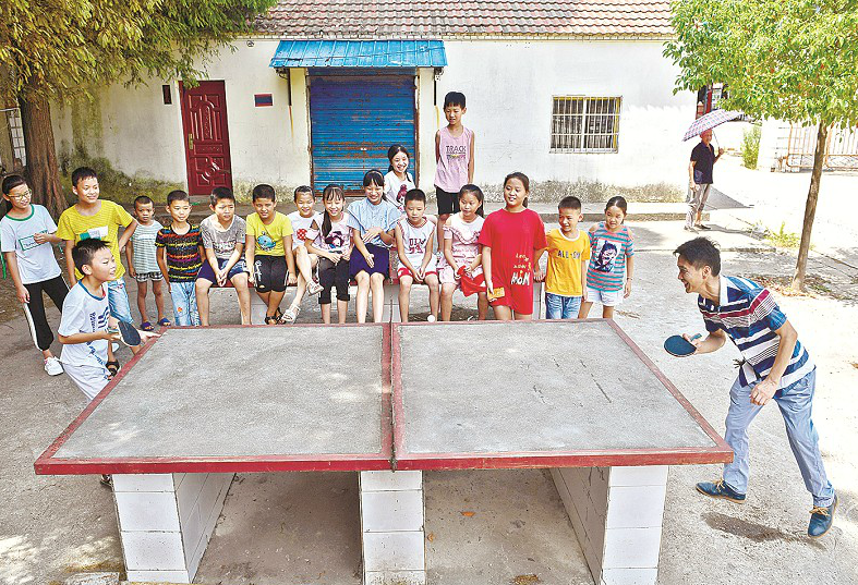 圖為:周永杰和學生一起打乒乓球