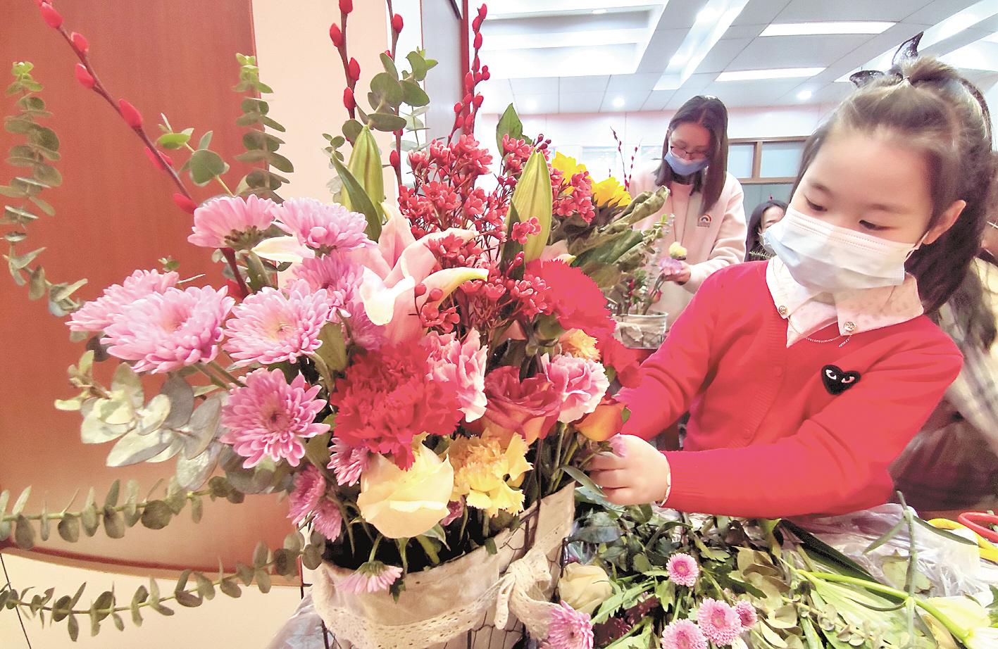 2月3日,武漢市江漢區唐家墩社區的小朋友在志愿者的指導下,插出了自己喜歡的迎春納福花籃。 (視界網 李長林 攝)