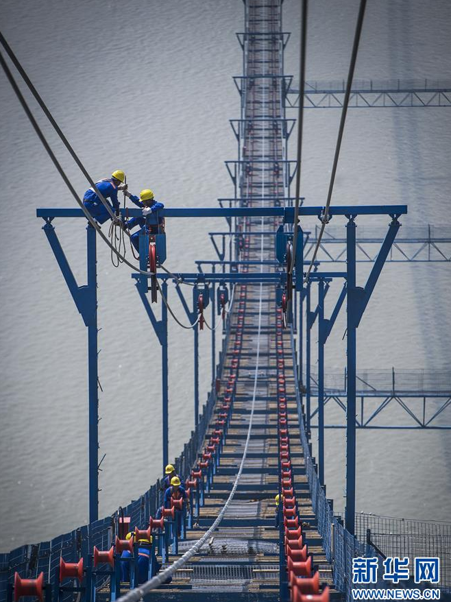 工人在高空中架設(shè)主纜(6月10日攝)。