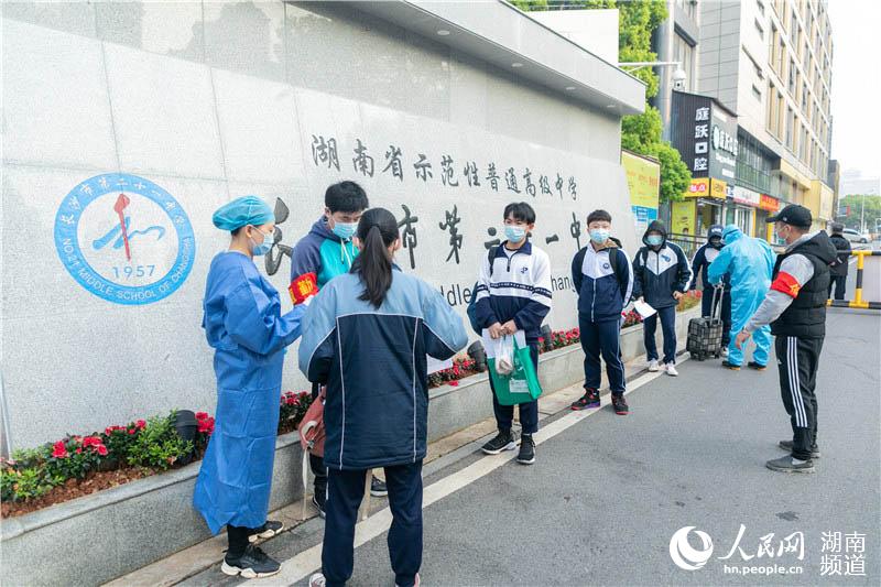 在長沙市第二十一中學,高三學生在校門口遞交健康卡。周軍 攝