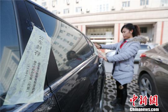 圖為工作人員給公務(wù)用車貼封條。 譚凱興 攝