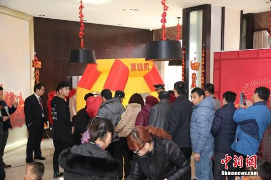 資料圖:2016年2月27日,山東東營(yíng),看房的市民在商家設(shè)置的“搶錢機(jī)”內(nèi)搶著飛舞的人民幣,搶到的人民幣歸市民所有。由于房地產(chǎn)市場(chǎng)低迷,山東東營(yíng)的某樓盤為了吸引前來看房的市民,在售樓處安裝了“搶錢機(jī)”,看房的市民排成長(zhǎng)隊(duì)“搶錢”,用真金白銀刺激看房客。 圖片來源:視覺中國