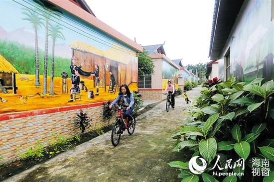 瓊海會山加腦村 游客在苗繡園村騎行